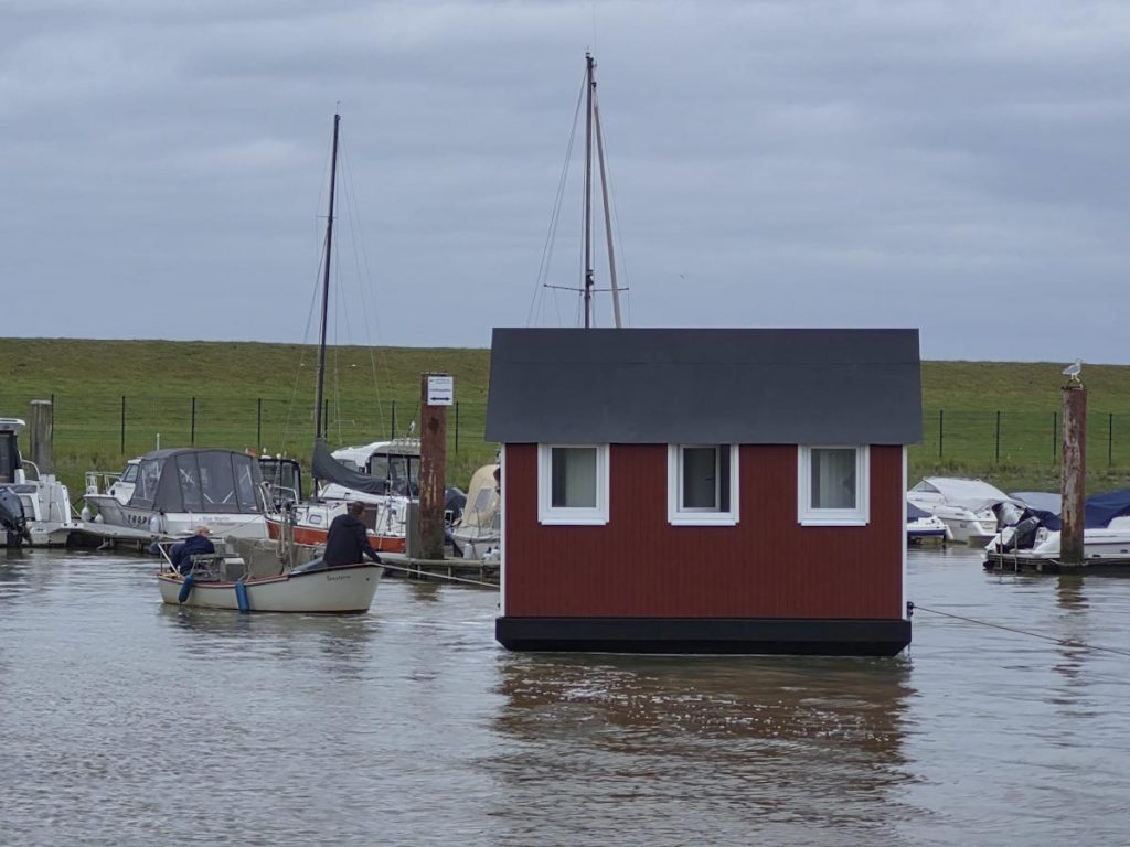 Ein kleines Boot zieht die Sanitäranlage auf ihren Liegeplatz im Hafen.